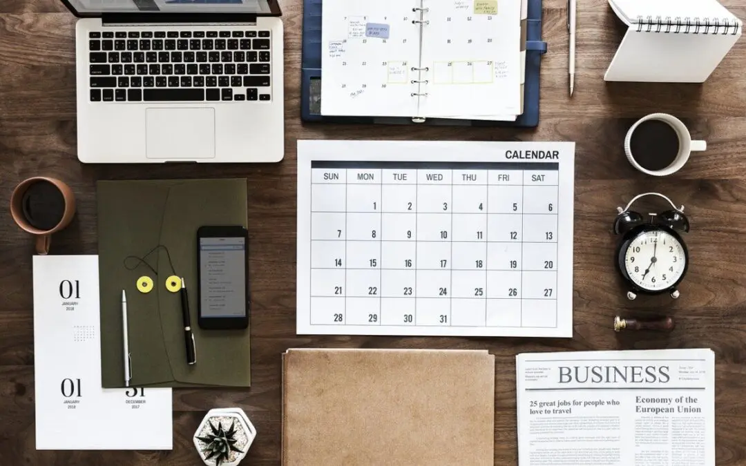 table with laptop, clock, calendar, phone, and coffee
